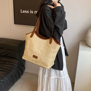 Grand sac cabas d'été en paille avec bandoulières en cuir marron porté par un mannequin