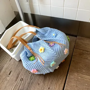 Light blue hand-knitted crochet tote bag with colorful 3D flowers and brown leather strap