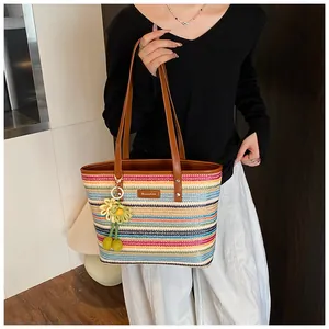 Rainbow striped woven tote bag with brown leather straps and yellow floral charm detail