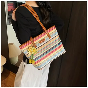 Close-up of rainbow woven tote bag with brown leather straps and flower charm
