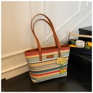 Detail of colorful striped straw tote bag with brown leather handles and sunflower charm