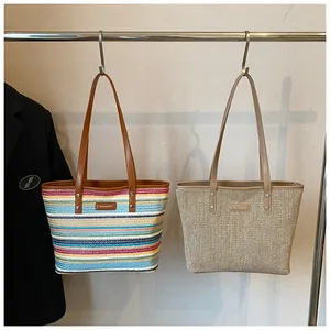 Detail of woven straw tote bags with colorful stripes and leather handles hanging on a rack