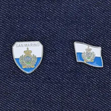 Detailed view of two San Marino national flag enamel pins on blue denim fabric background