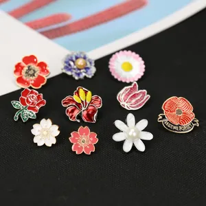 Set di 10 spille floreali in smalto colorato con fiori di ciliegio e perle su tessuto nero