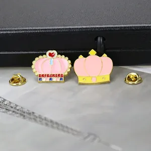 Détail de deux broches en forme de couronne émaillée avec cœurs et fermoirs papillon