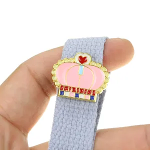 Vue macro d'un pin's couronne en émail rose avec bords dorés et détail de cœur