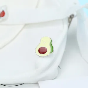Dettaglio di una spilla in smalto a forma di avocado su una borsa di tela