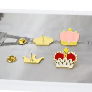 Détail de deux épingles de couronne en émail avec fermoirs papillon dorés sur carte grise