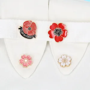 Detailansicht von vier floralen Emaille-Broschen mit rotem Mohn und Kirschblüten auf Hemd