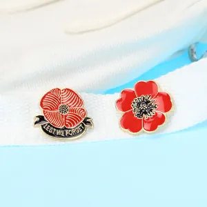 Detail von roten Emaille-Mohn-Broschen mit Lest We Forget Text auf weißem Gurtband