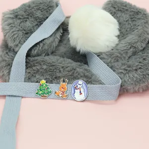 Gros plan de broches de Noël en émail avec sapin, renne et bonhomme de neige sur ruban bleu