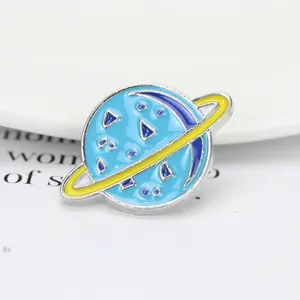 Détail d'une broche Saturne en émail bleu avec anneau jaune et contour en métal argenté