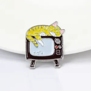 Gros plan d'un pin's en émail avec un chat rayé dormant sur un téléviseur vintage violet