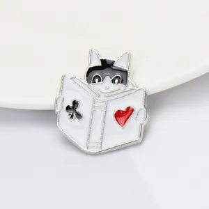 Macro détaillée d'une broche chat en émail lisant un livre sur une assiette blanche