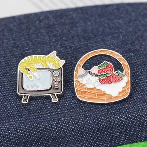 Détails de broches en émail représentant un chat sur une télé et dans un panier de fraises