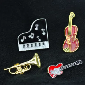 Detail view of four musical instrument enamel pins including a piano, violin and trumpet
