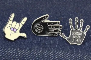 Dettaglio macro di tre spille punk in smalto inclusa una mano di scheletro su denim blu