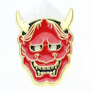 Dettaglio della spilla in smalto a forma di maschera Hannya rossa con placcatura in oro