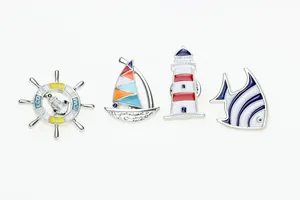 Detailed macro view of enamel nautical pins including anchor, sailboat and lighthouse