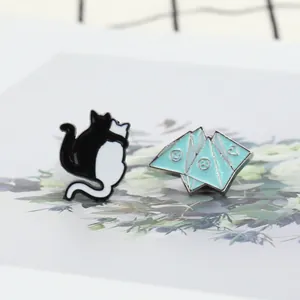 Detail of blue geometric enamel pin with glitter and minimal black white cat badges