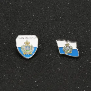 Detailed view of San Marino national flag and shield enamel pins on black textured surface