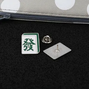 Vue détaillée de la broche Mahjong avec caractère traditionnel vert et fermoir papillon