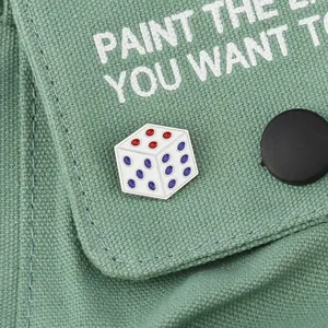 Gros plan détaillé d'une broche dé en émail blanc fixée sur un sac en toile verte