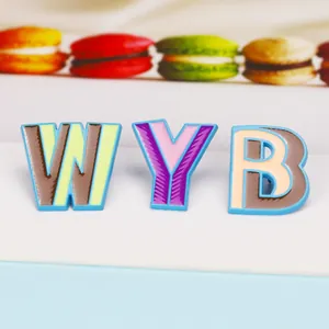 Detail view of colorful WYB enamel letter brooches with vibrant striped patterns