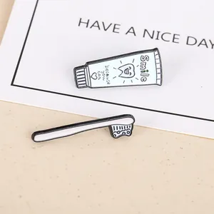 Detail shot of cartoon enamel pins featuring a blue toothpaste tube and a white toothbrush