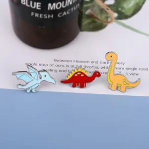 Detailed macro view of three colorful enamel dinosaur pins featuring blue red and yellow designs