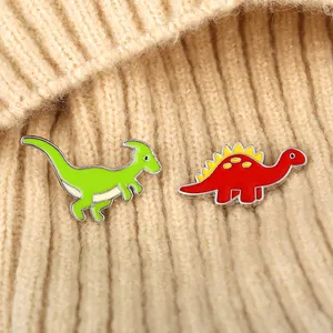 Detailed view of colorful enamel dinosaur brooches on beige knitted fabric background