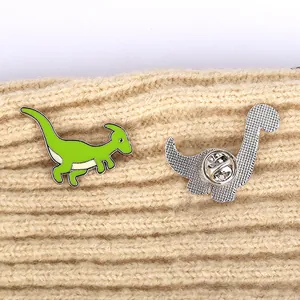 Cute green enamel dinosaur brooches with butterfly clasp on beige knit fabric