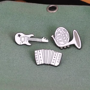 Cartoon musical instrument enamel pins set including guitar and accordion on green fabric