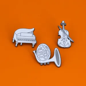 Cartoon musical instrument enamel pins set featuring piano violin and horn on orange background