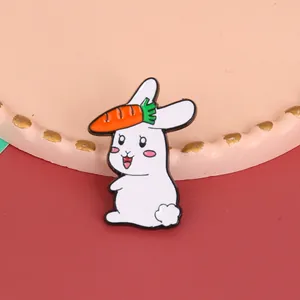 Close-up of cute white enamel bunny brooch with carrot detail on polished metal surface