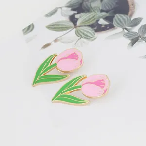 Elegant pink tulip brooches with green leaves and gold trim on white background