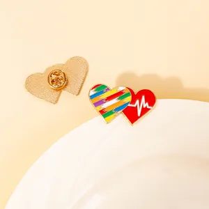 Detail showing two rainbow heart enamel brooches with golden metal butterfly clutch pins