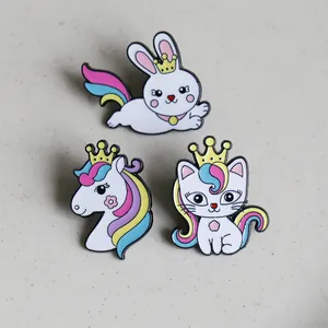 Detail of colorful enamel pins featuring a rabbit, unicorn, and cat with golden crowns