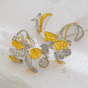 Détail de bagues en acier bicolore avec motifs de fleurs et de cœur sur pierre
