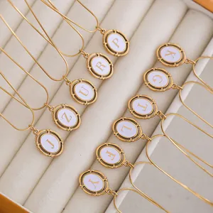 Macro detail of oval alphabet pendants with gold plating on golden snake chains