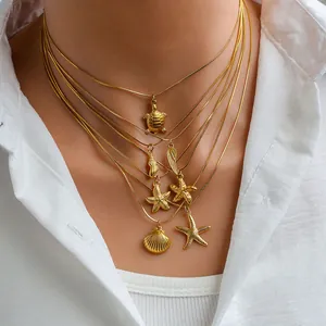 Close-up of layered gold ocean necklaces with turtle, starfish and shell charms