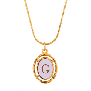 Close-up of gold oval letter G pendant on sleek snake chain with white inlay