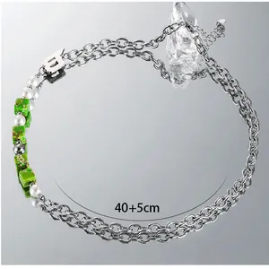 Close-up of double-layer chain necklace with pearls, green stones, and letter B pendant
