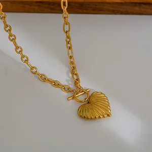 Macro detail of gold chunky chain heart pendant necklace with vintage pleated texture and OT buckle
