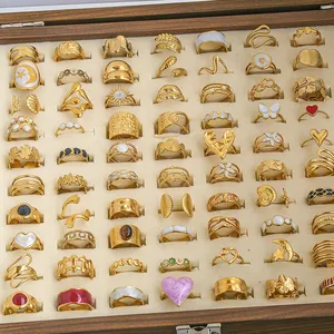 Detailed top view of various vintage enamel and pearl silver rings in a wooden box