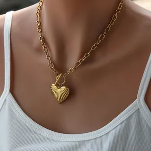 Detail of golden chunky link chain necklace with heart pendant and toggle clasp