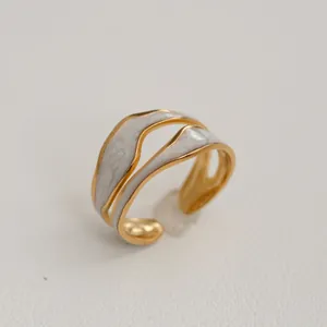 Détail d'une bague réglable en acier inoxydable plaqué or avec émail effet marbre blanc