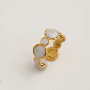 Vue détaillée de la bague en acier inoxydable doré avec des détails circulaires en émail blanc