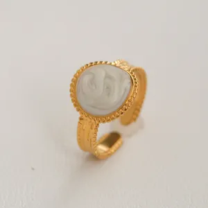 Détail d'une bague dorée réglable avec incrustation de marbre blanc et bord perlé