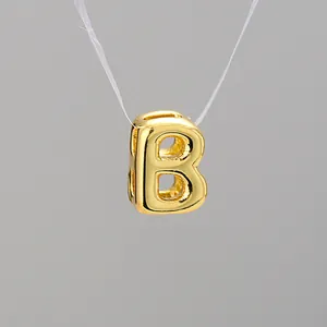 Macro detail of a 3D bubble letter B gold-plated pendant with polished metallic finish